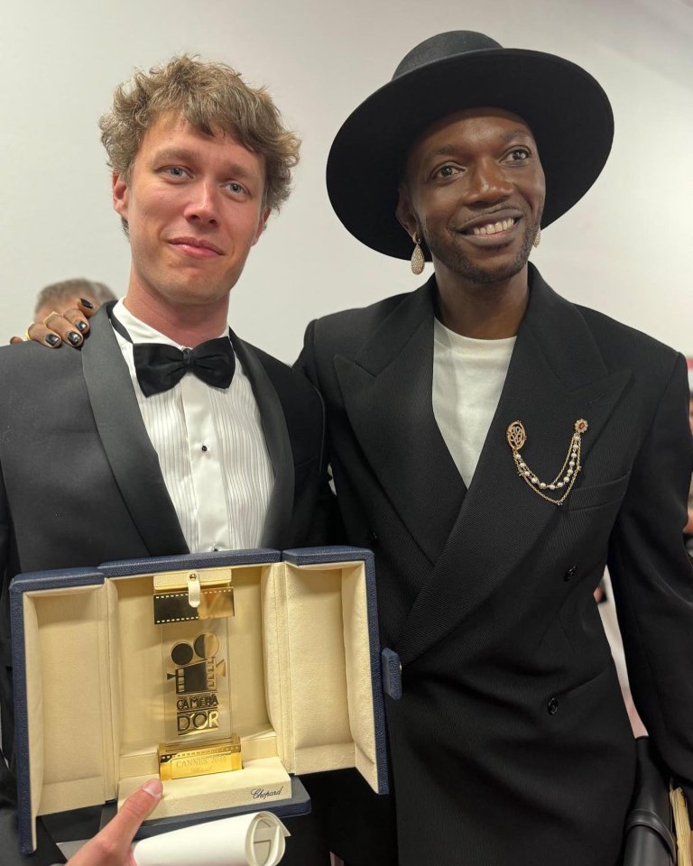 Two men smiling into camera, one holding an award