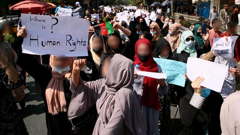 Women with their faces blurred holding a poster where it says "Where is human rights?"